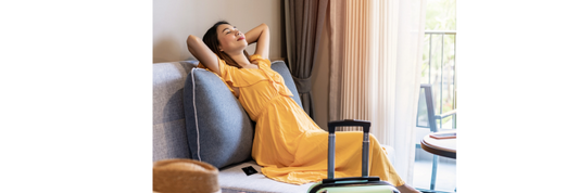Asian Woman on couch relaxing with travel suitcase